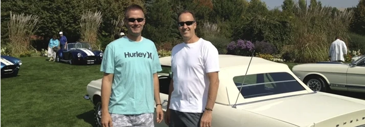 Dr. Lamar C. Fox and Dr. Floyd P. Huxford standing on grass next to a classic car, with other vintage cars in the background.
