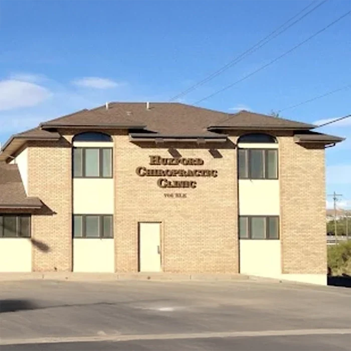 Brick building exterior with multiple windows and a sign reading “Huxford Chiropractic Clinic” on the front.